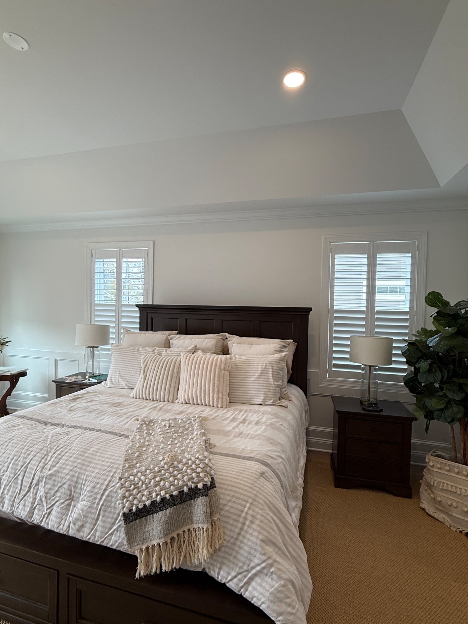 Master bedroom symmetrical plantation shutters dark wood headboard